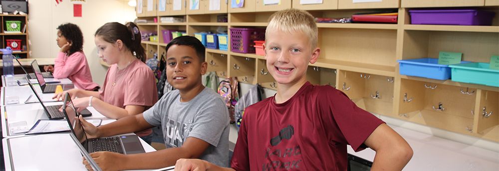 kids at desks using laptops