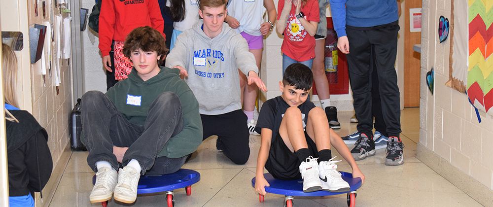 high school boy and fourth grade boy racing on scooters.