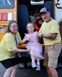 Bus drivers helping girl out of back of bus.