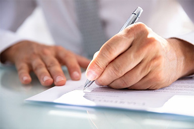 A hand using a pen to fill out a form.