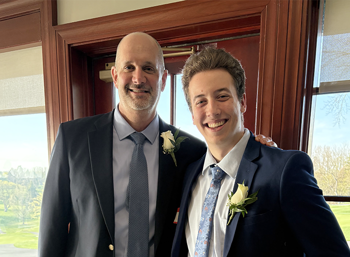 A tall man standing with a tall teen.
