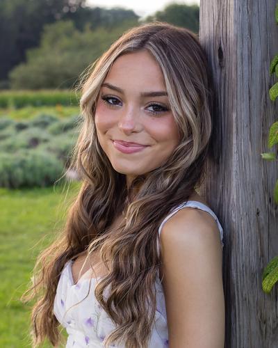 Teen leaning against a tree.