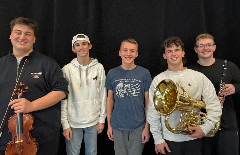 Four teen boys with one holding a violin and one holding a euphonium.