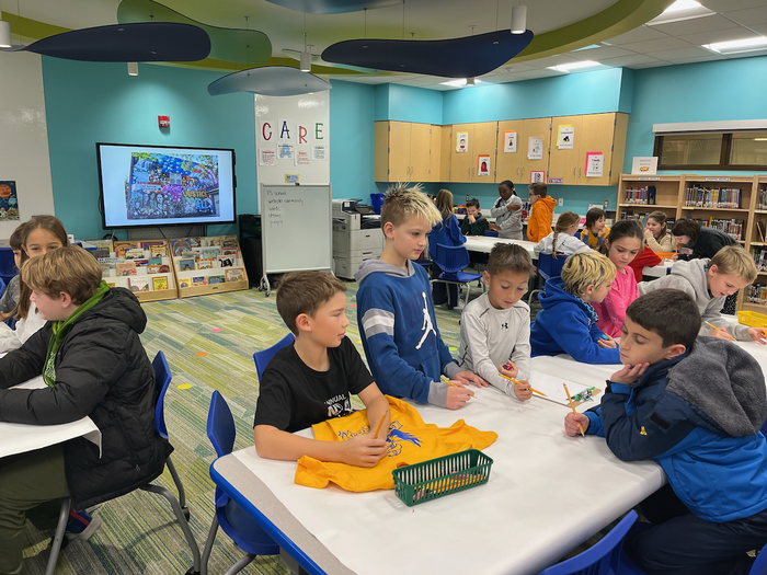 Groups of fourth graders talking at tables.