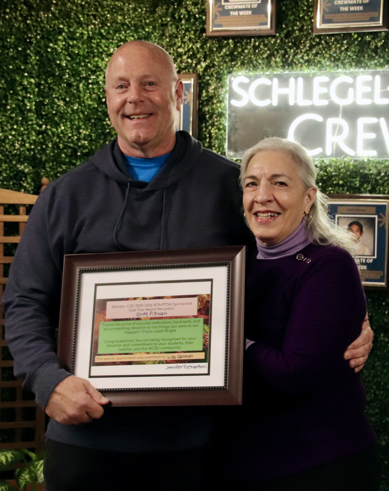 Man and woman standing together with man holding plaque.
