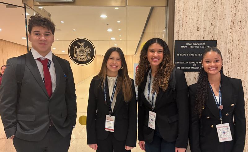 Four teens dressed in suits standing in a row.
