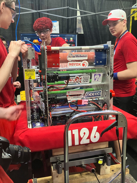 Three teens working on a robot.
