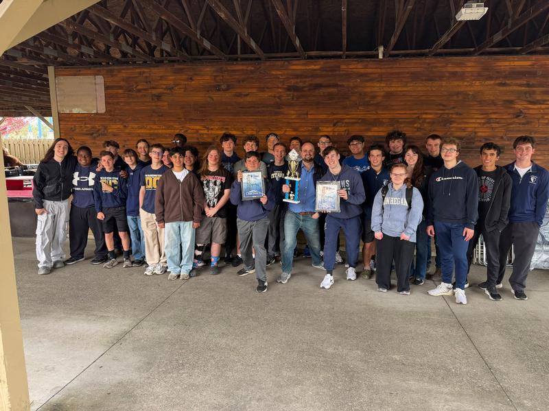Large group of teens and teachers holding trophies.