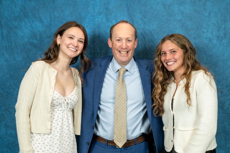 Two teens standing with a man. All are smiling.