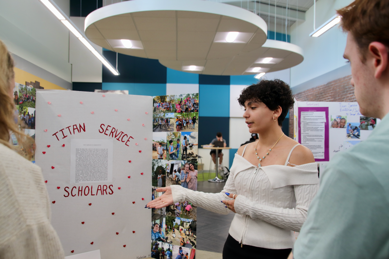 Teen directing attention to a posterboard with information on it.