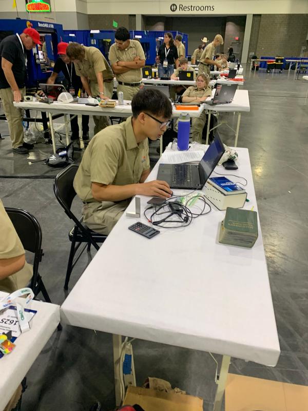 A teen working on a laptop and durrounded by wires.