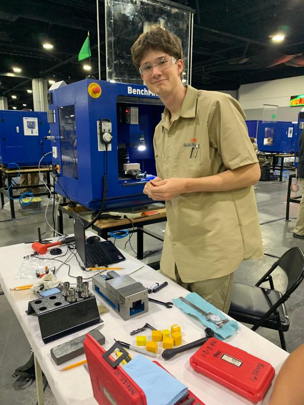 A teen with a laptop and tools on a table in front of him.