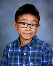 Boy with black glasses and wearing blue, white and gray checked shirt