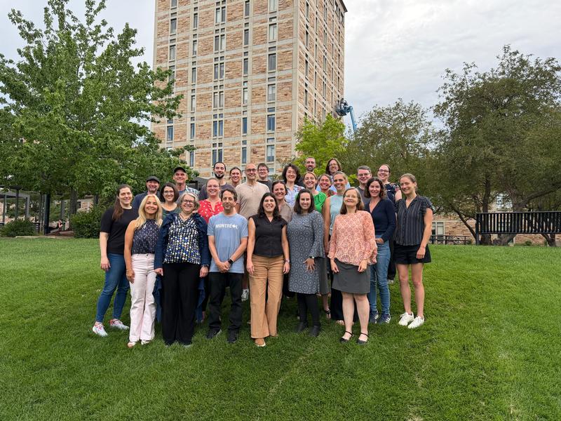 Group of adults on a lawn with a tall building in the background.