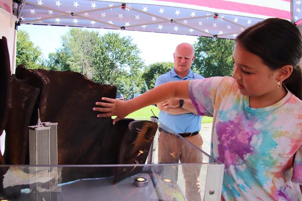 A fifth grader gently touches a large piece of gnarled steel.