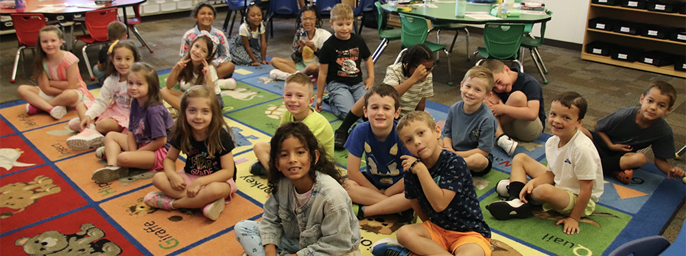 classroom children sitting on a colorful carpet