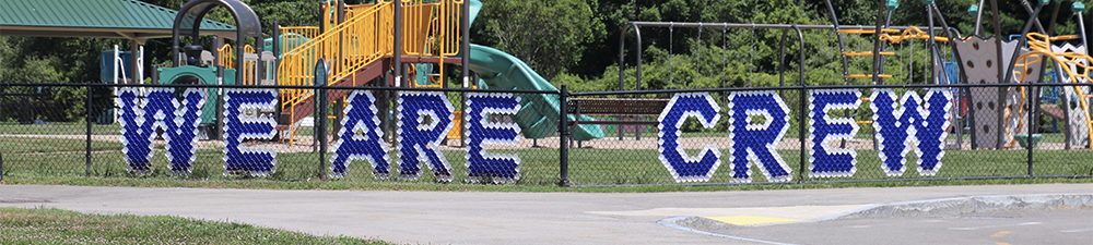 A playground with the words WE ARE CREW on the fence surrounding it.