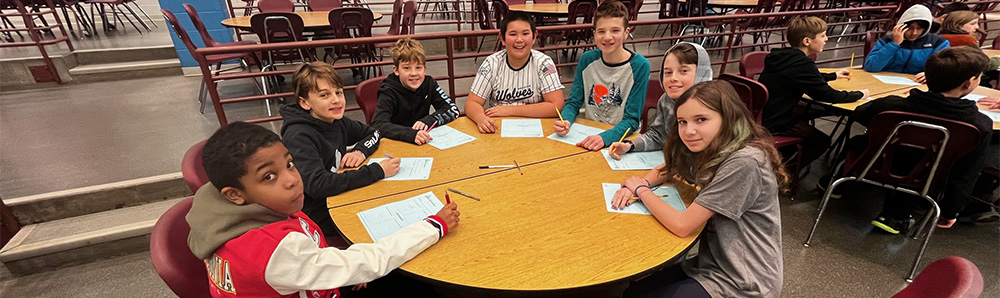 Seven sixth grade students sitting around a circular table.